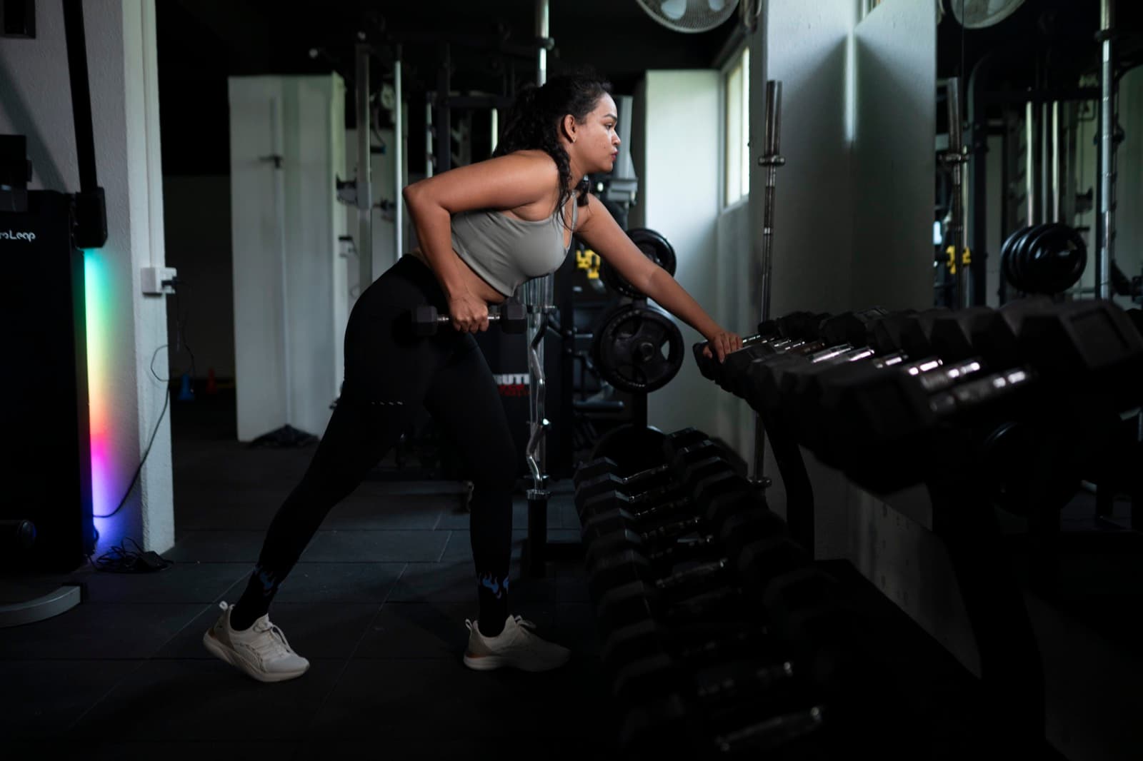 A FIT360 client performing a single-arm dumbbell row in cinematic light