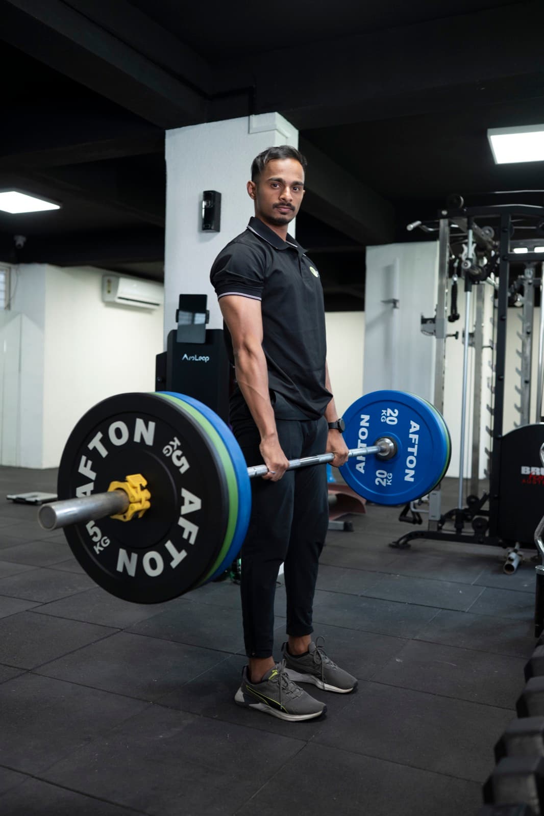 Coach Lucky standing tall with a barbell at the top of a deadlift